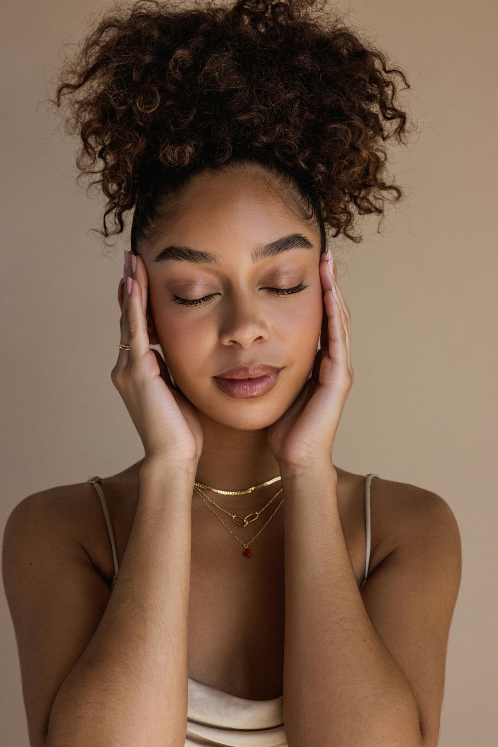 Dedham Hydrafacial model with curly hair, eyes closed, peaceful expression.